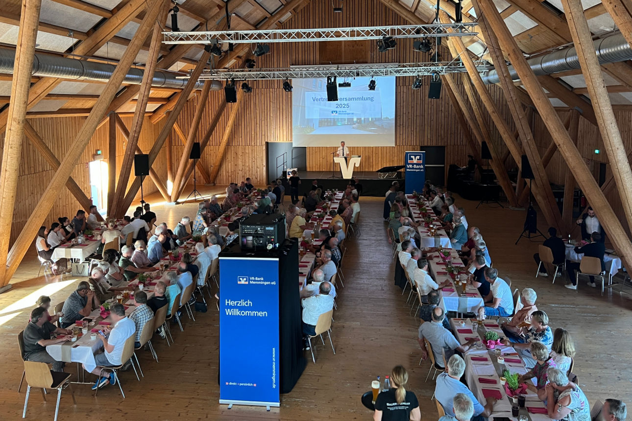 Raum während der Vertreterversammlung mit Tischen, Vertretern und Bühne mit Präsentation