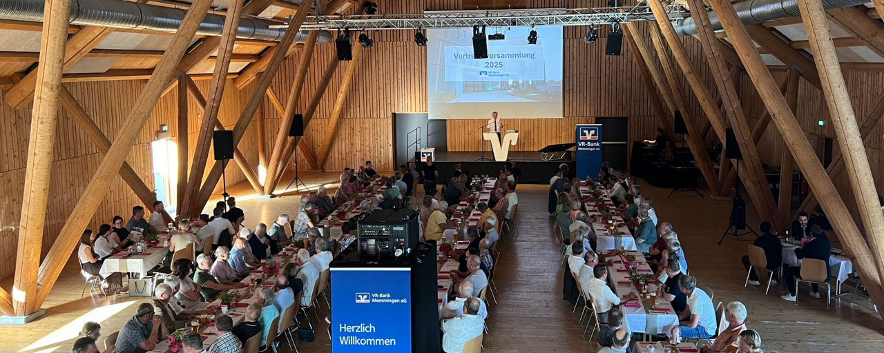 Raum während der Vertreterversammlung mit Tischen, Vertretern und Bühne mit Präsentation