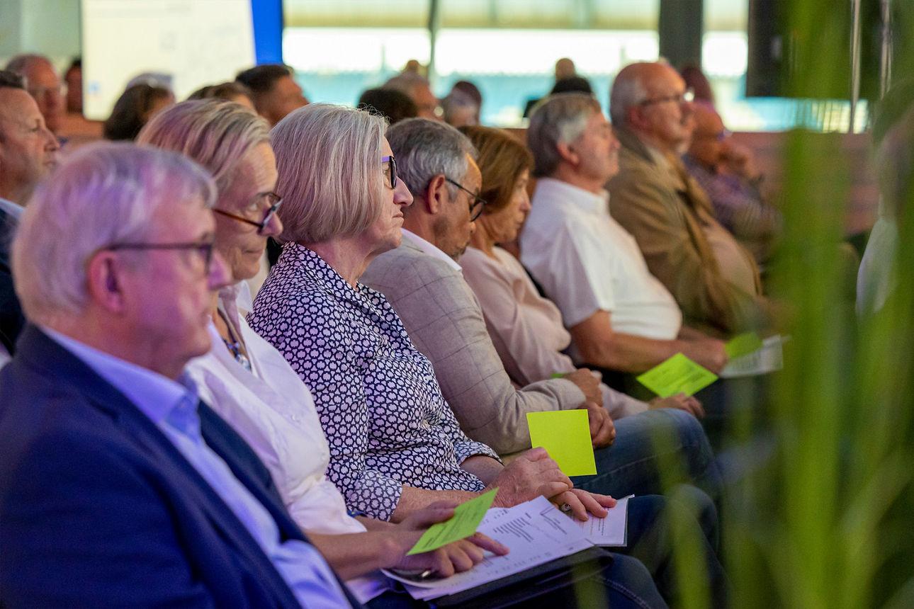 Foto unserer Vertreterversammlung. Das Bild zeigt Menschen im Saal mit Stimmkarten
