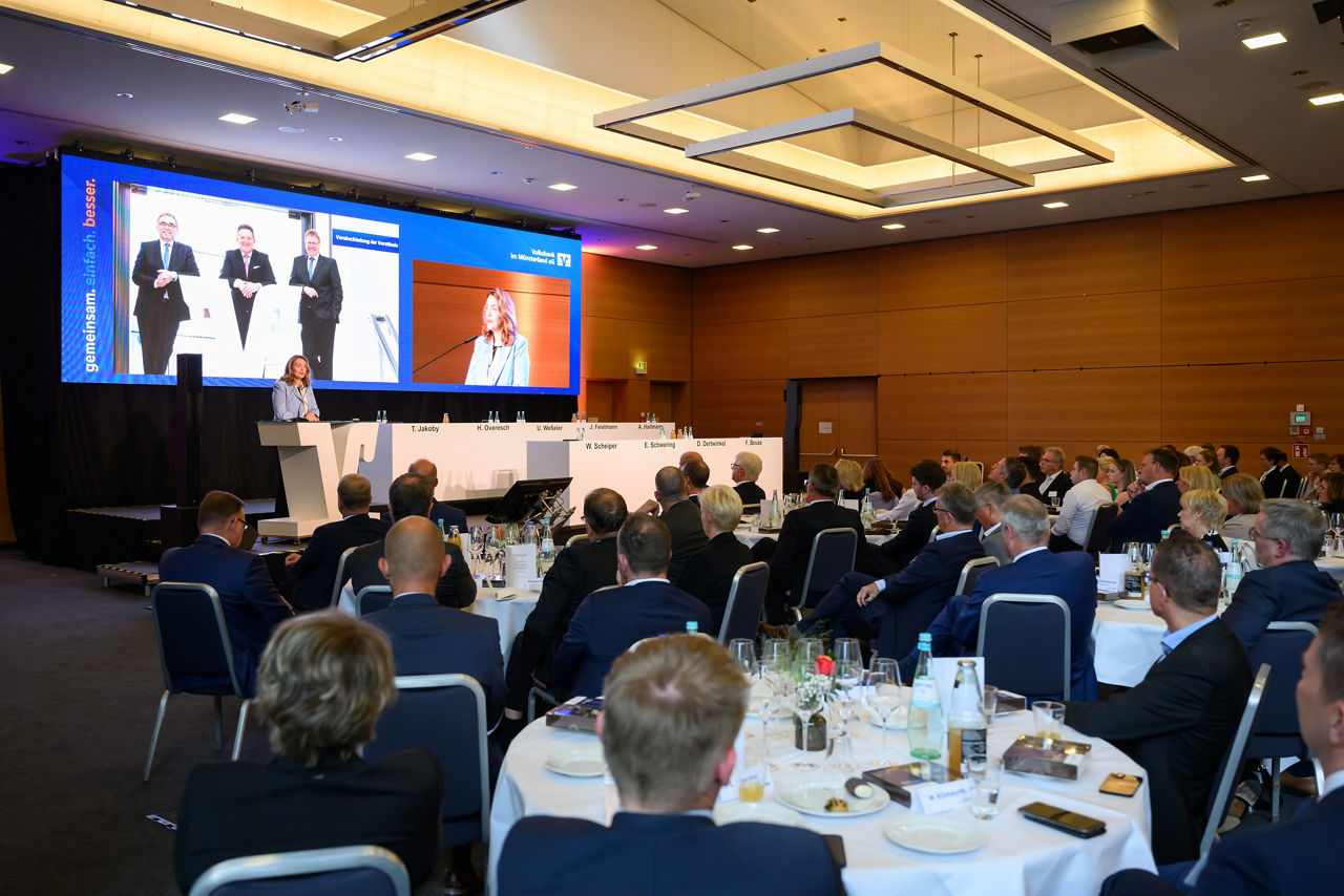 Verabschiedung der Vorstände auf der Vertreterversammlung im Juni 2024 mit vielen Menschen in einem Saal mit einer Bühne