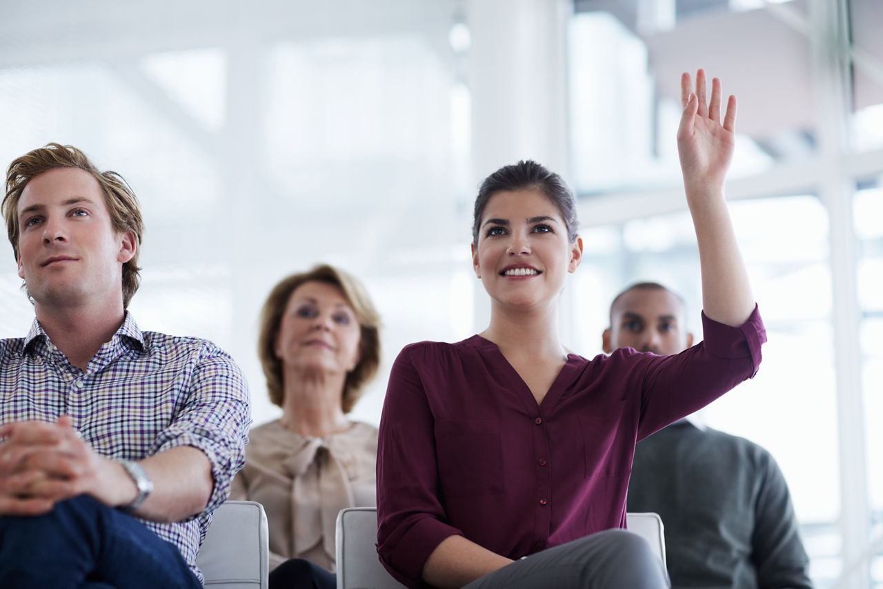 Smiling businesswoman asking question in seminar at office