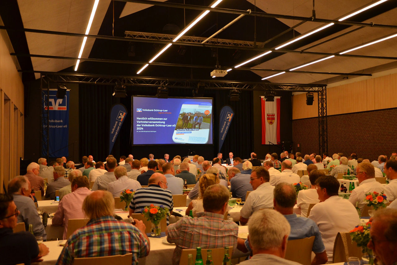 ein Konferenzraum mit Teilnehmern, die an runden Tischen sitzen.