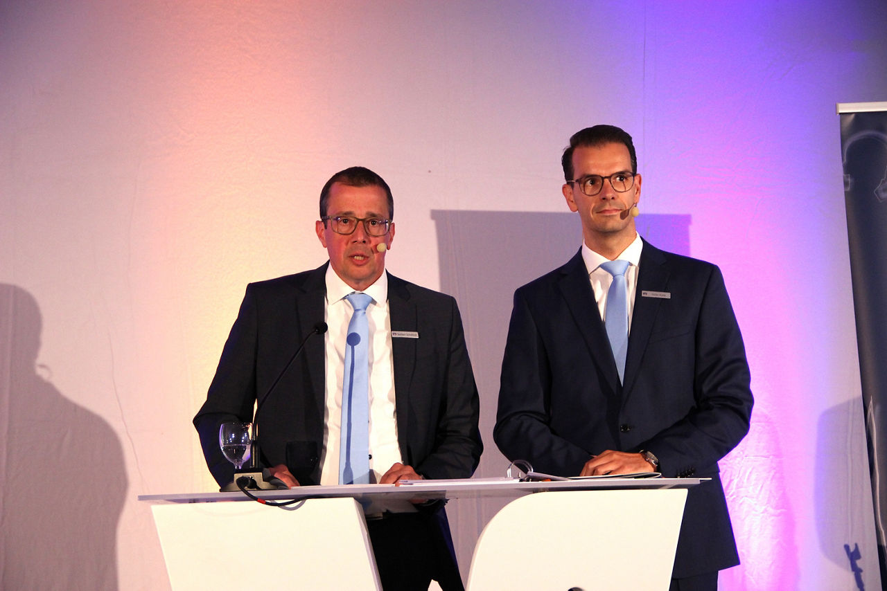 Auf der Vertreterversammlung der Volksbank Schermbeck stehen die Vorstände Norbert Scholtholt und Stefan Korte nebeneinander am Rednerpult. 