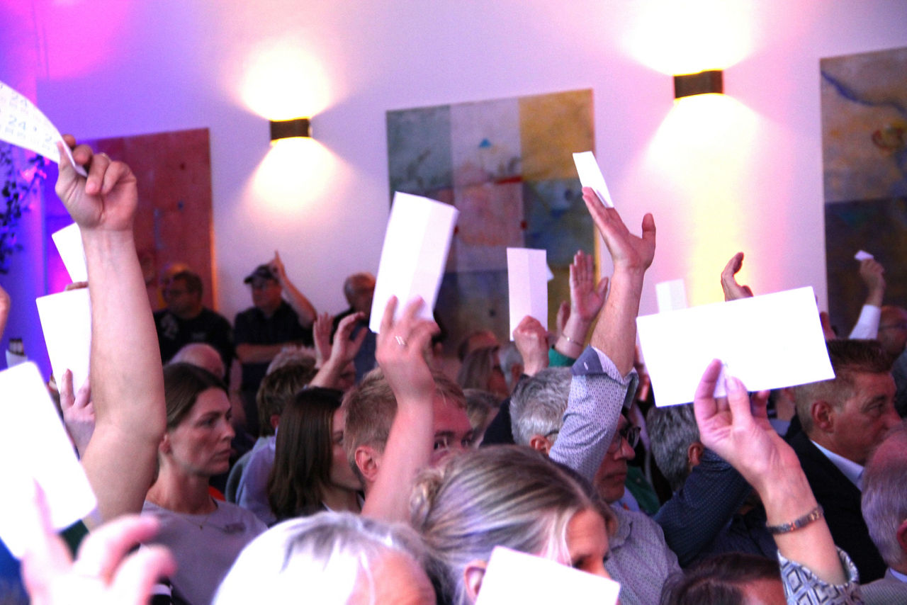 Eine Personengruppe die Stimmkarten in den Händen halten