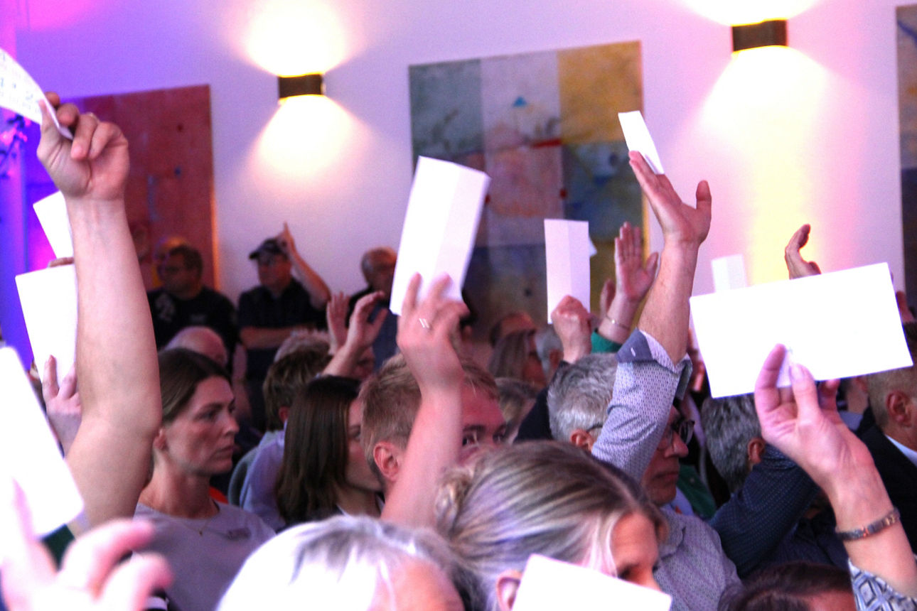 Eine Personengruppe die Stimmkarten in den Händen halten