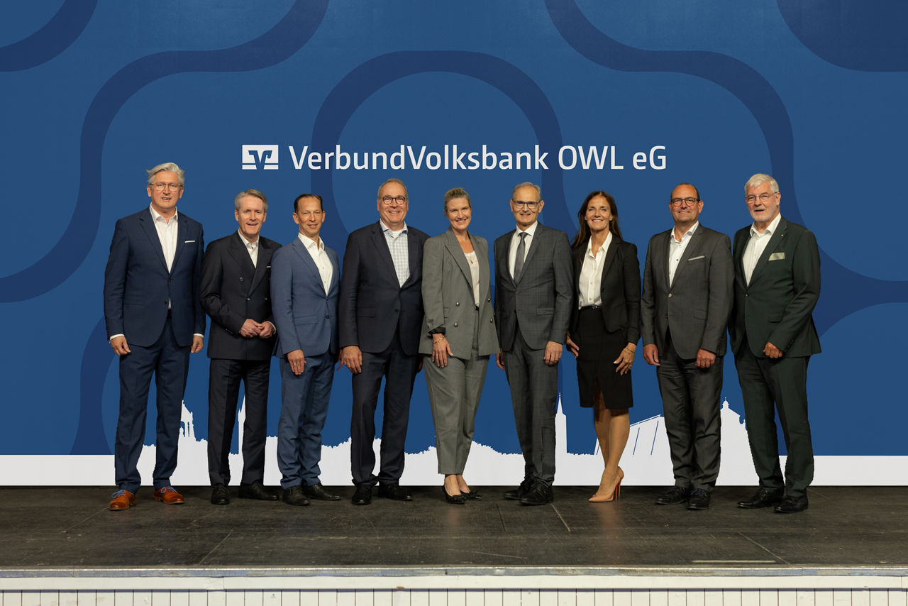 Vorstandsmitglieder und Aufsichtsratsmitglieder der VerbundVolksbank OWL eG stehen auf der Bühne.
