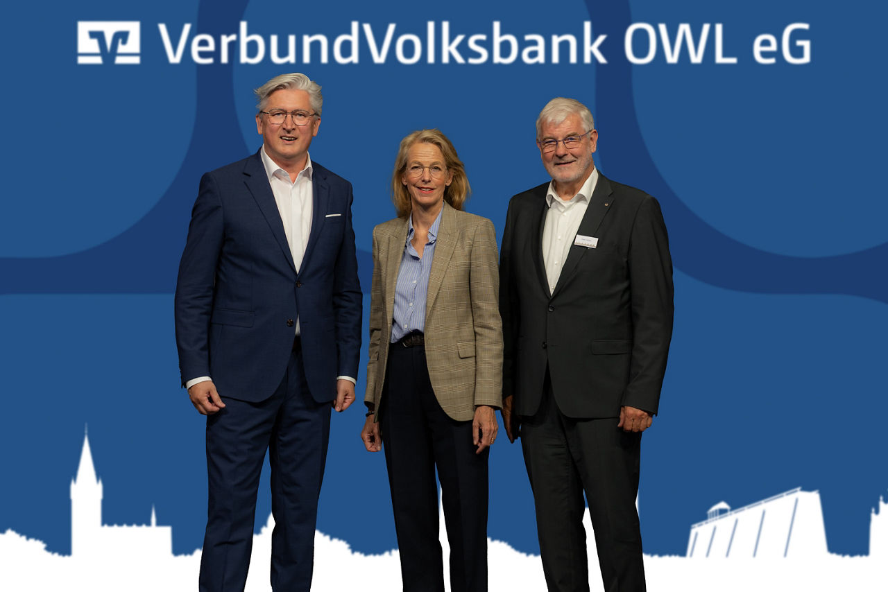 Der Vorstandsvorsitzende und der Aufsichtsratsvorsitzende der VerbundVolksbank OWL eG stehen gemeinsam mit der Gastreferentin Julia Jäkel auf der Bühne.