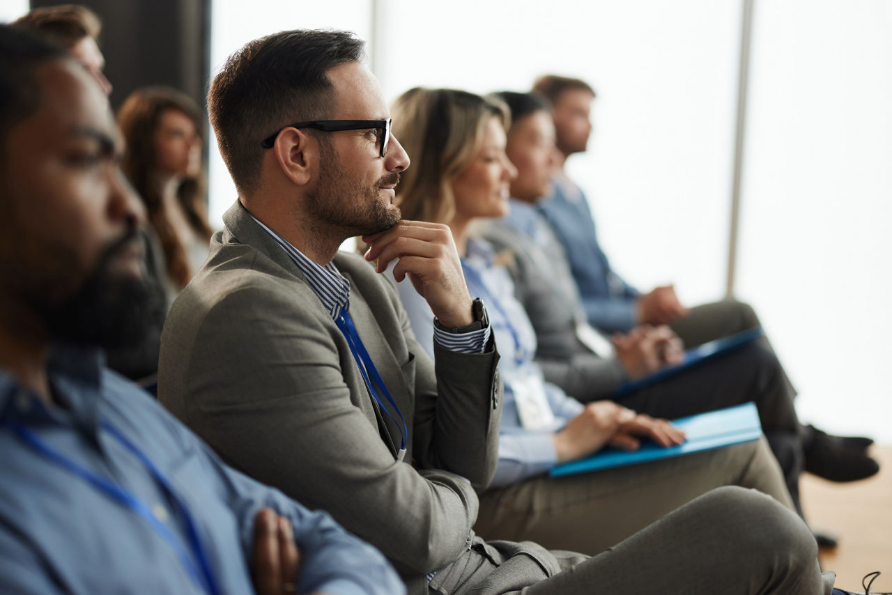 Profile view of smiling businessman and group of his colleagues attending a seminar in board room.