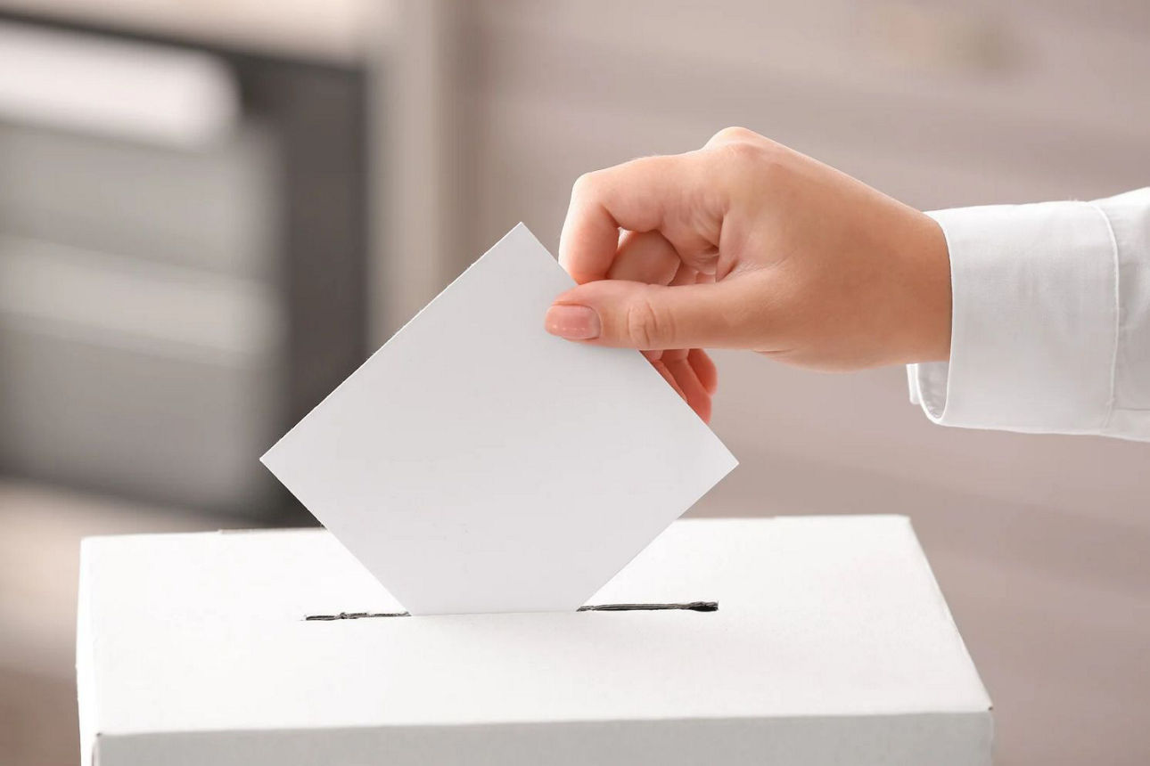 Wahlschein wird in Wahlurne geworfen