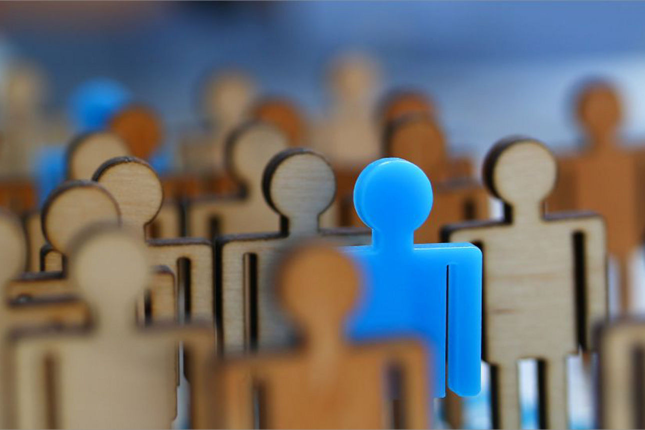 eine Gruppe Holzfiguren, bei der eine blaue Figur heraussticht