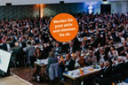Viele Menschen sitzen in einem großen Saal zusammen
