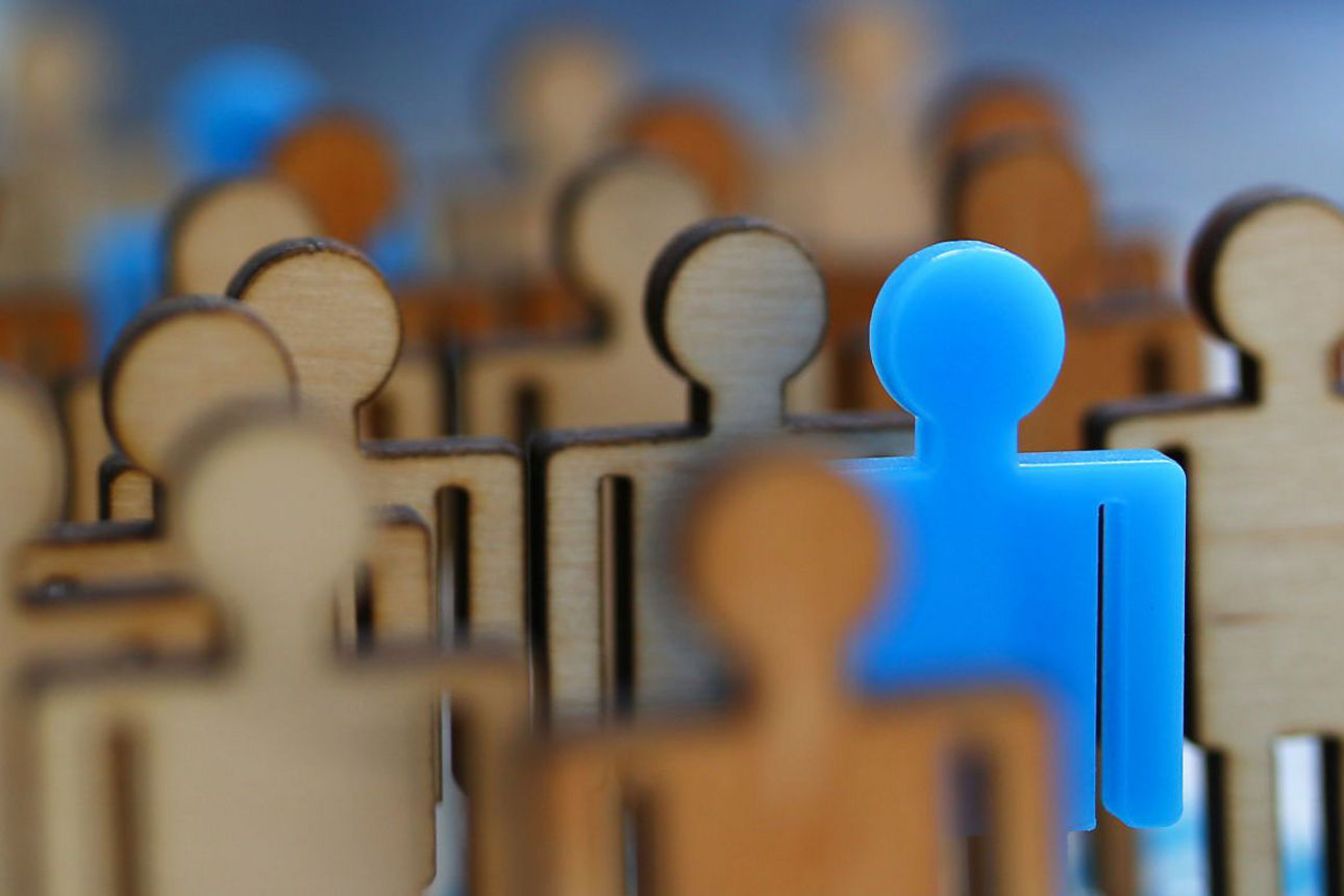 eine Gruppe Holzfiguren, bei der eine blaue Figur heraussticht