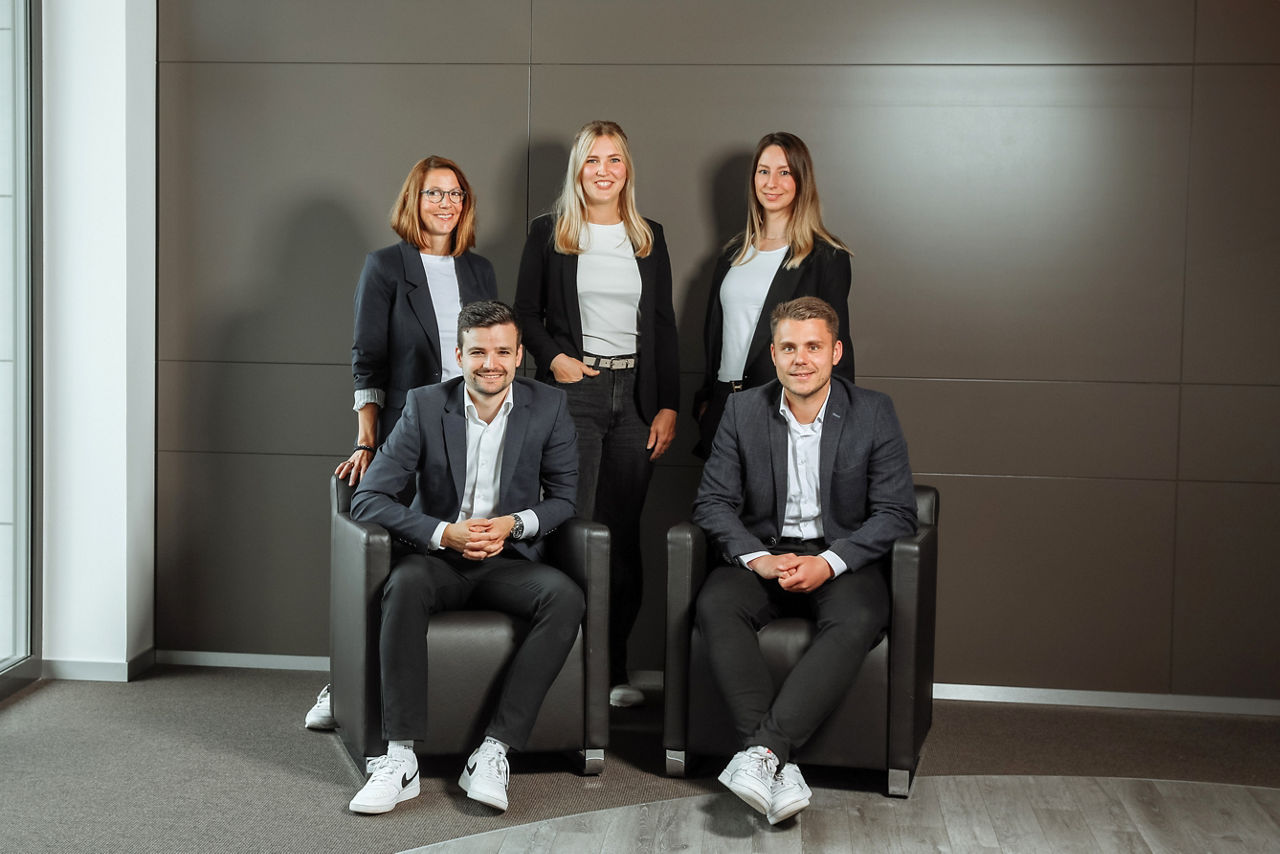 Mitarbeiterteam stehend und sitzend fünf Personen