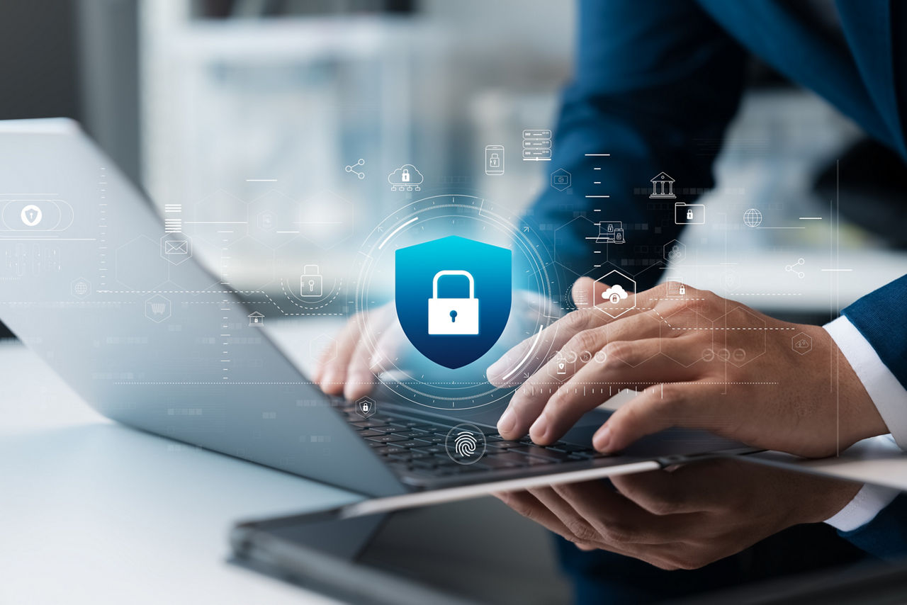 Eine Person tippt auf einem Laptop, über dem ein digitales Schloss-Symbol erscheint