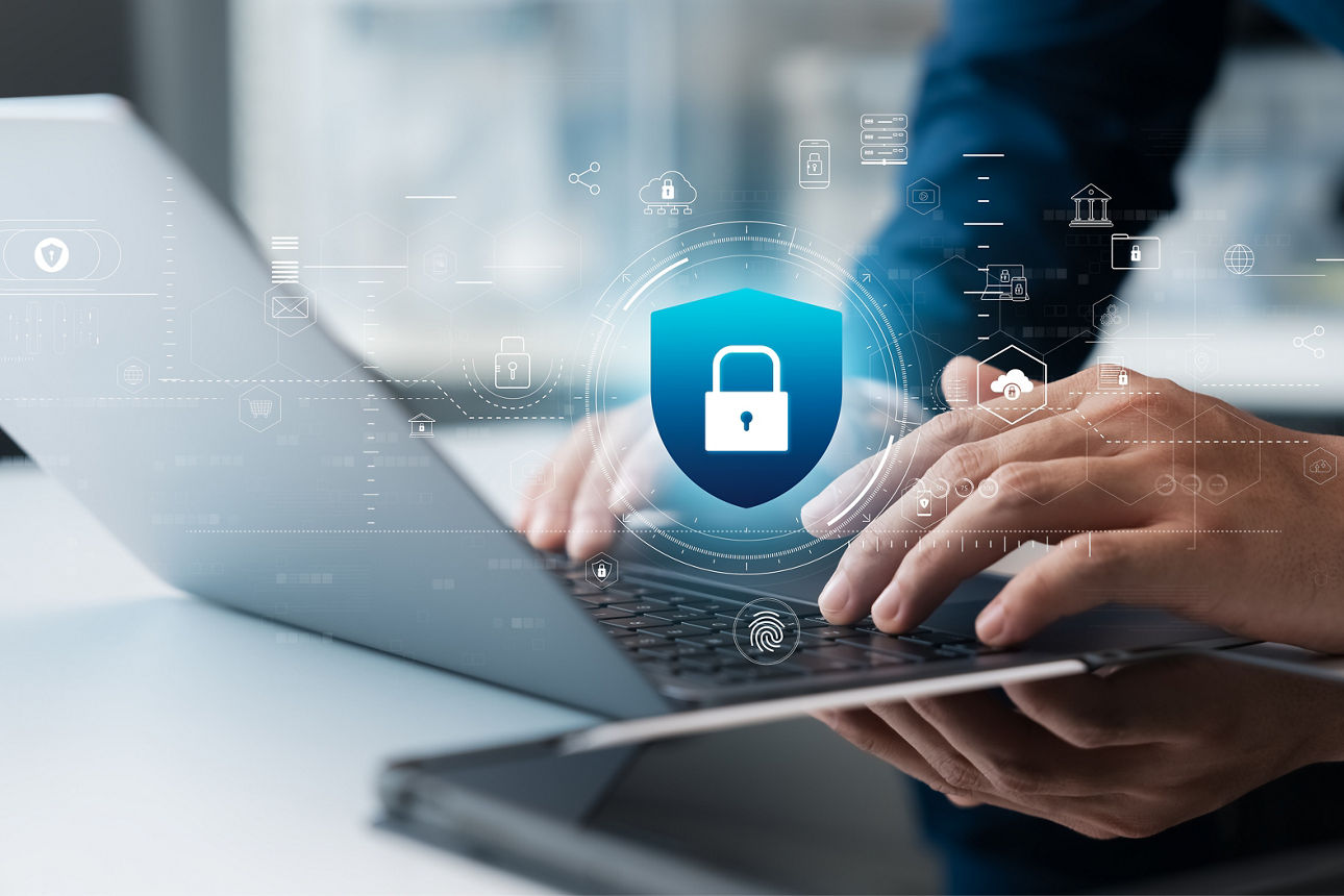 Eine Person tippt auf einem Laptop, über dem ein digitales Schloss-Symbol erscheint