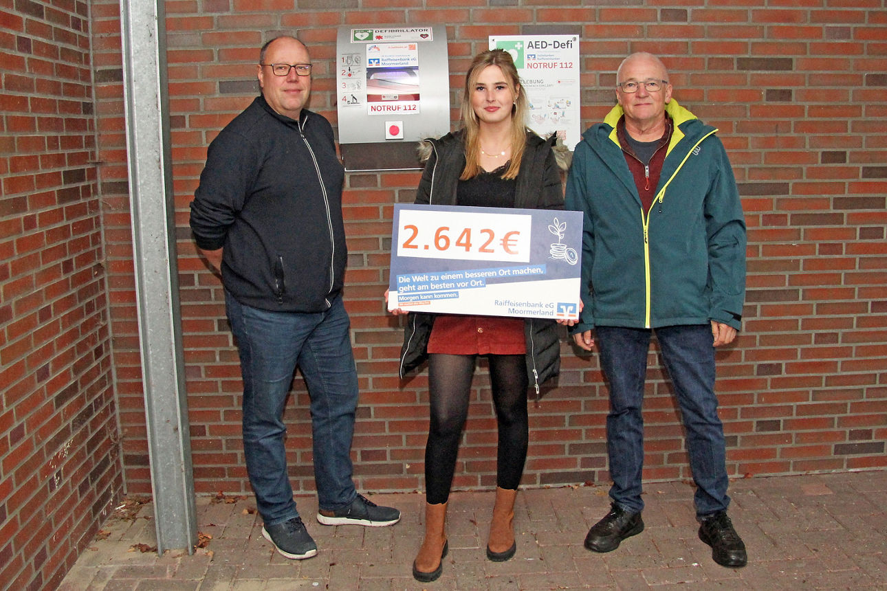 Gruppenbild vor dem angeschafften Defibrillator