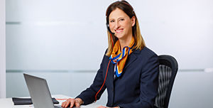 Eine Mitarbeiterin, die am Schreibtisch sitzt und per Video eine Beratung durchführt