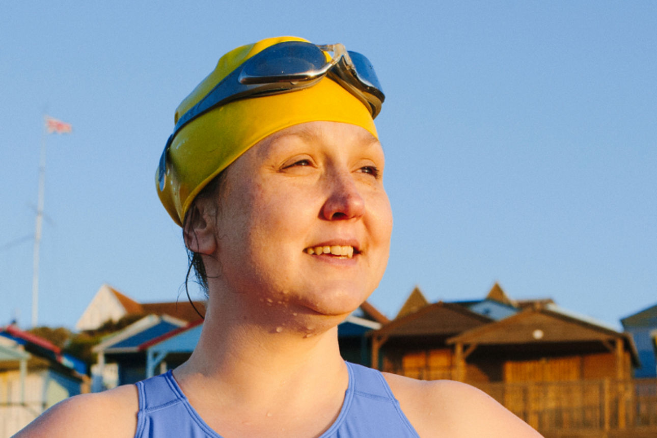 Eine Dame mit Badeanzug, Badehaube und Schwimmbrille am Strand