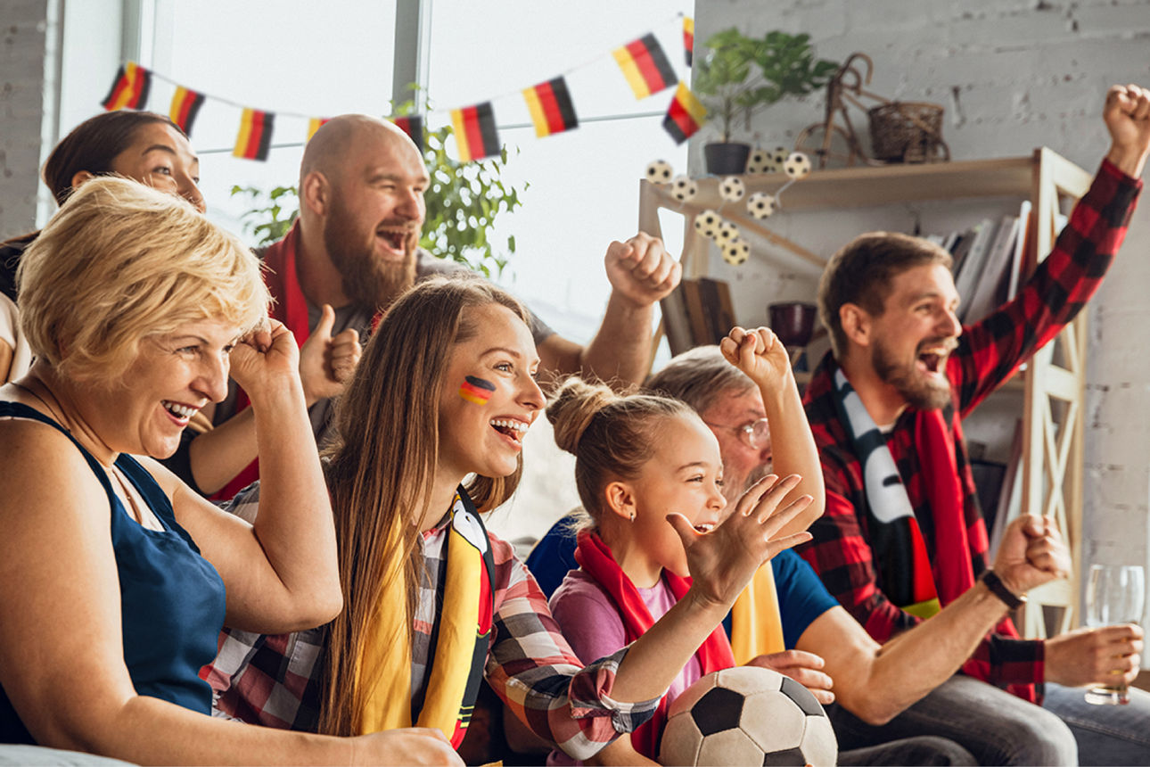 Jubelnde Fans in einem mit Deutschlandfahnen dekoriertem Raum