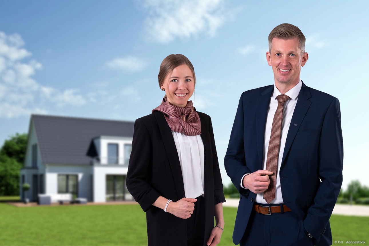 Zwei Geschäftsleute im Anzug stehen lächelnd vor einem unscharfen, modernen Einfamilienhaus im Grünen unter blauem Himmel.