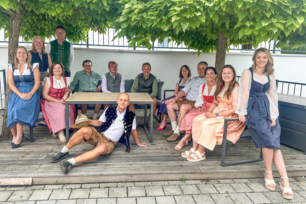 Eine gesellige Gruppe verbringt gemeinsam Zeit auf einer begrünten Terrasse und steht für Gemeinschaft, Begegnung und ein her