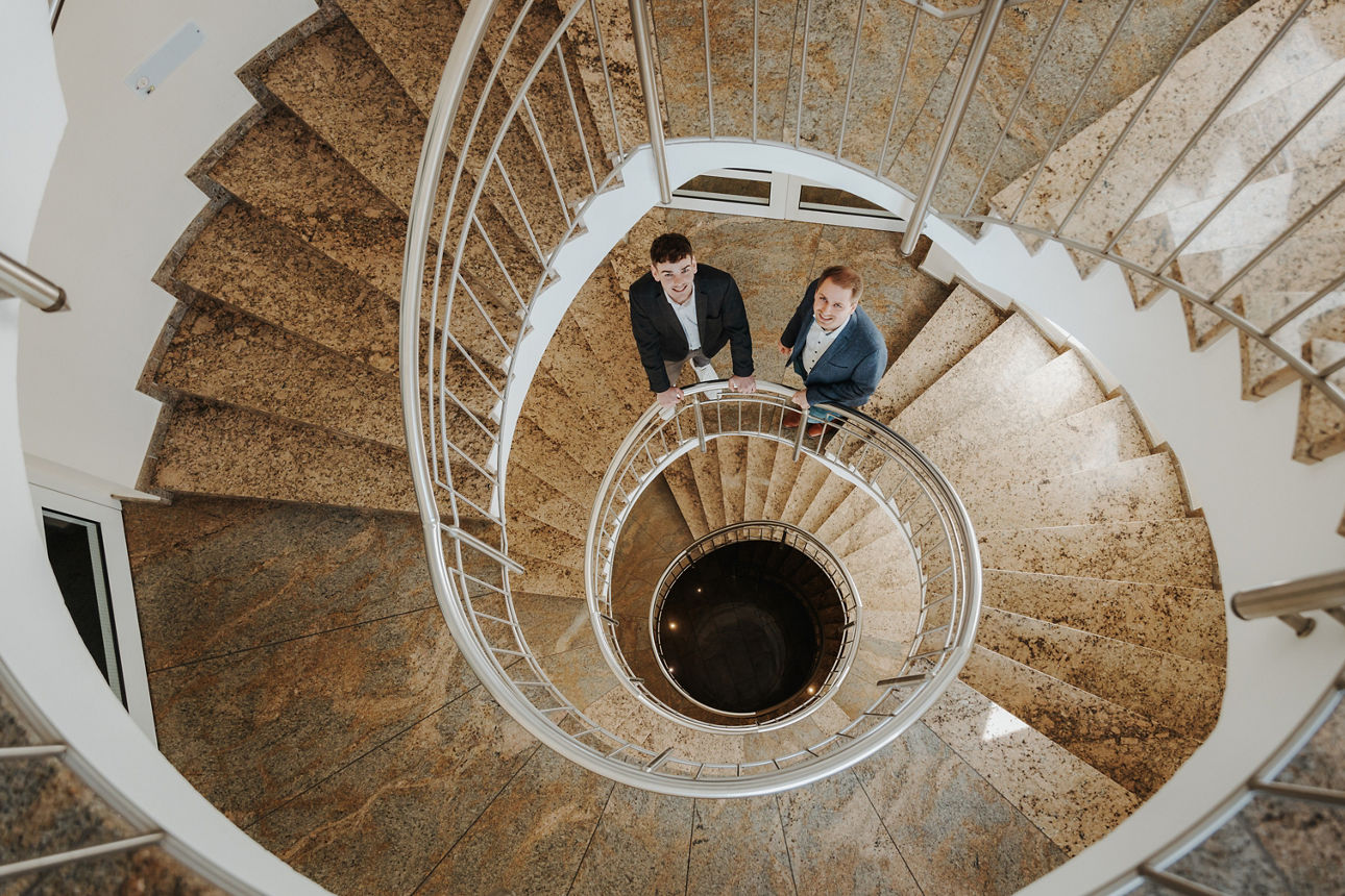Eine lange Wendeltreppe in Hameln mit unseren zwei Kollegen die hochschauen.