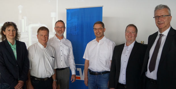 Das Bild zeigt eine Gruppe von Personen, die gemeinsam für ein Foto posieren. Sie tragen formelle Kleidung, darunter Anzüge u