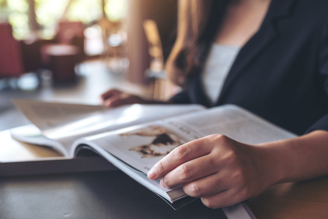 Nahaufnahme einer Geschäftsfrau, die in einem modernen Café ein Buch liest.