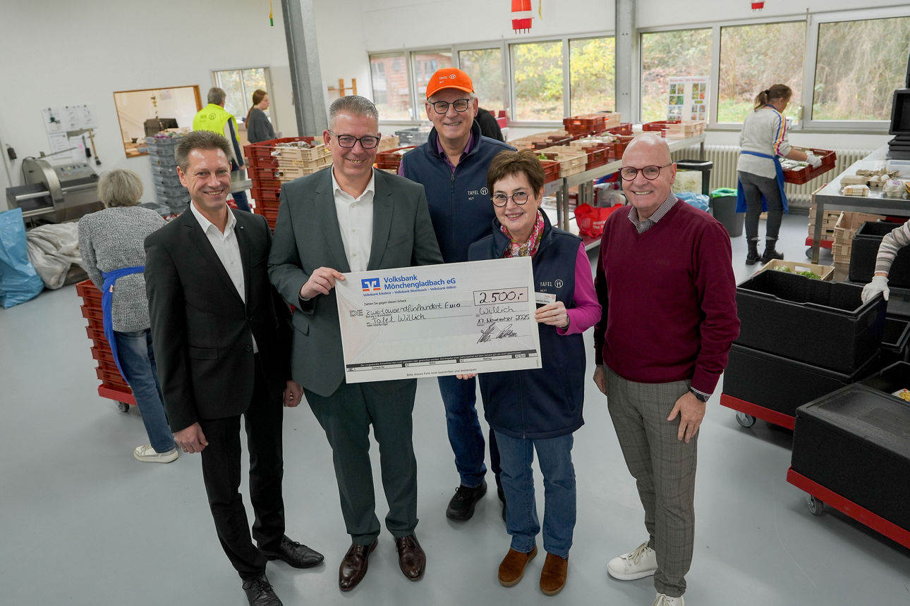 Das Foto zeigt eine Gruppe von fünf Erwachsenen, die in einem hellen, gut organisierten Raum einer Lebensmittelausgabe stehen