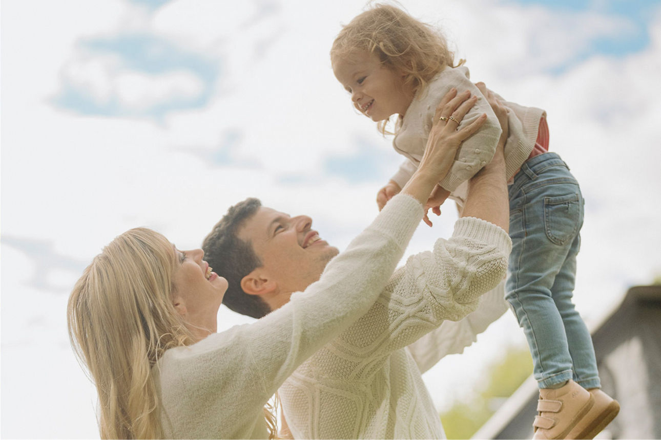 Eine junge Familie hält ihr Mädchen in die Luft