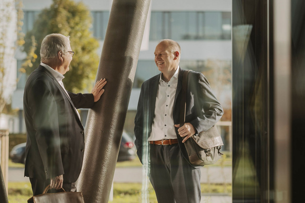 Zwei Männer treffen sich am Morgen vor der Arbeit vor einem Gebäude