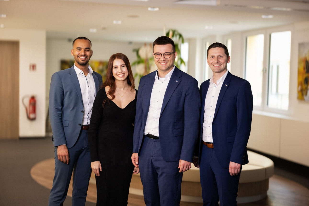 Eine lächelnde Frau und drei lächelnde Männer im Wartebereich