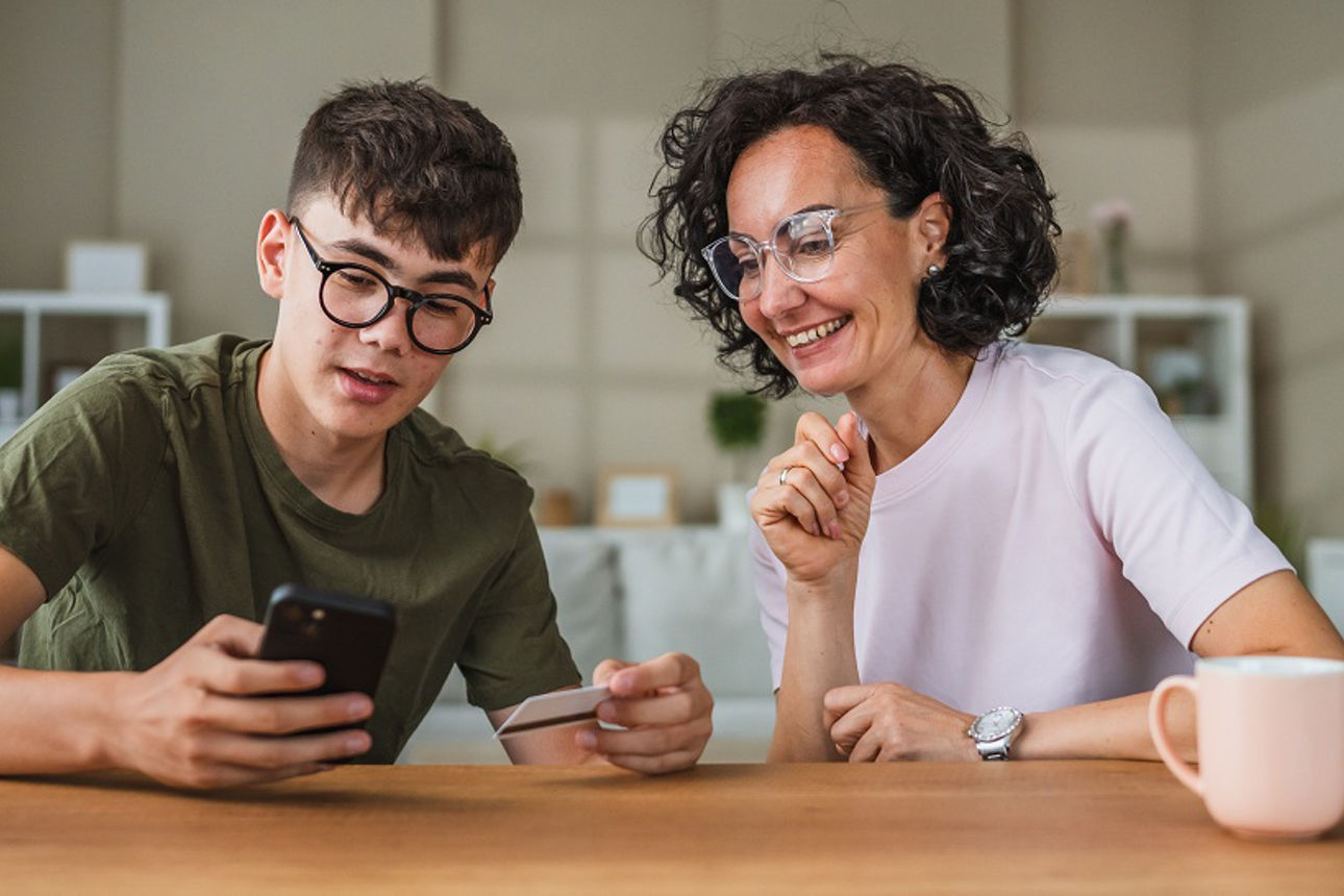 Mutter und Sohn mit einer Bankkarte und einem Smartphone