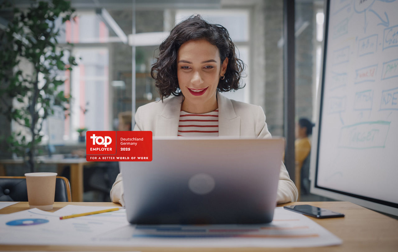 Gut gelaunte Frau über Laptop an einem modernen Arbeitsplatz