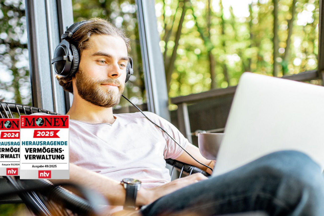 Junger Mann mit Kopfhörer auf sitzt entspannt am Laptop