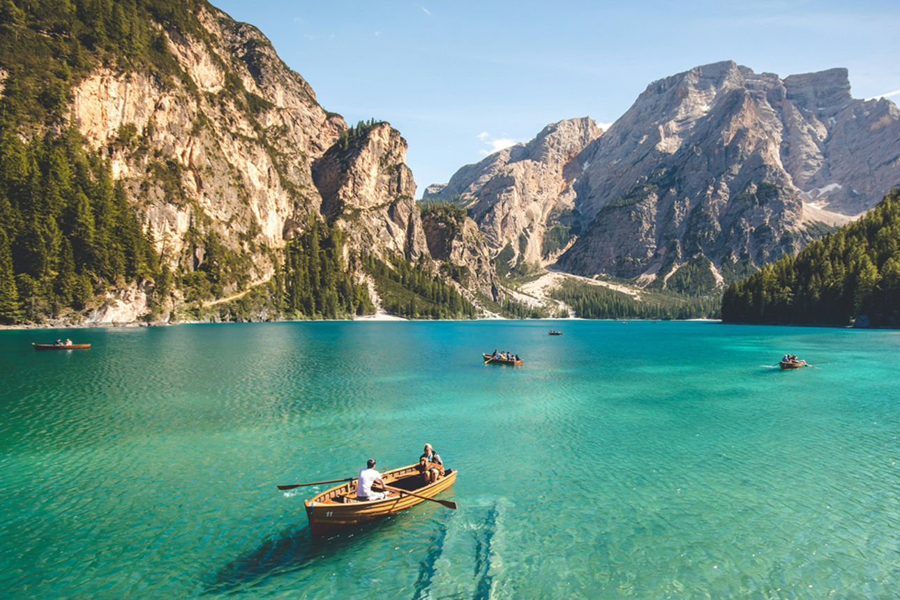 Urlaubsmotiv mit See, Ruderbooten und Bergen