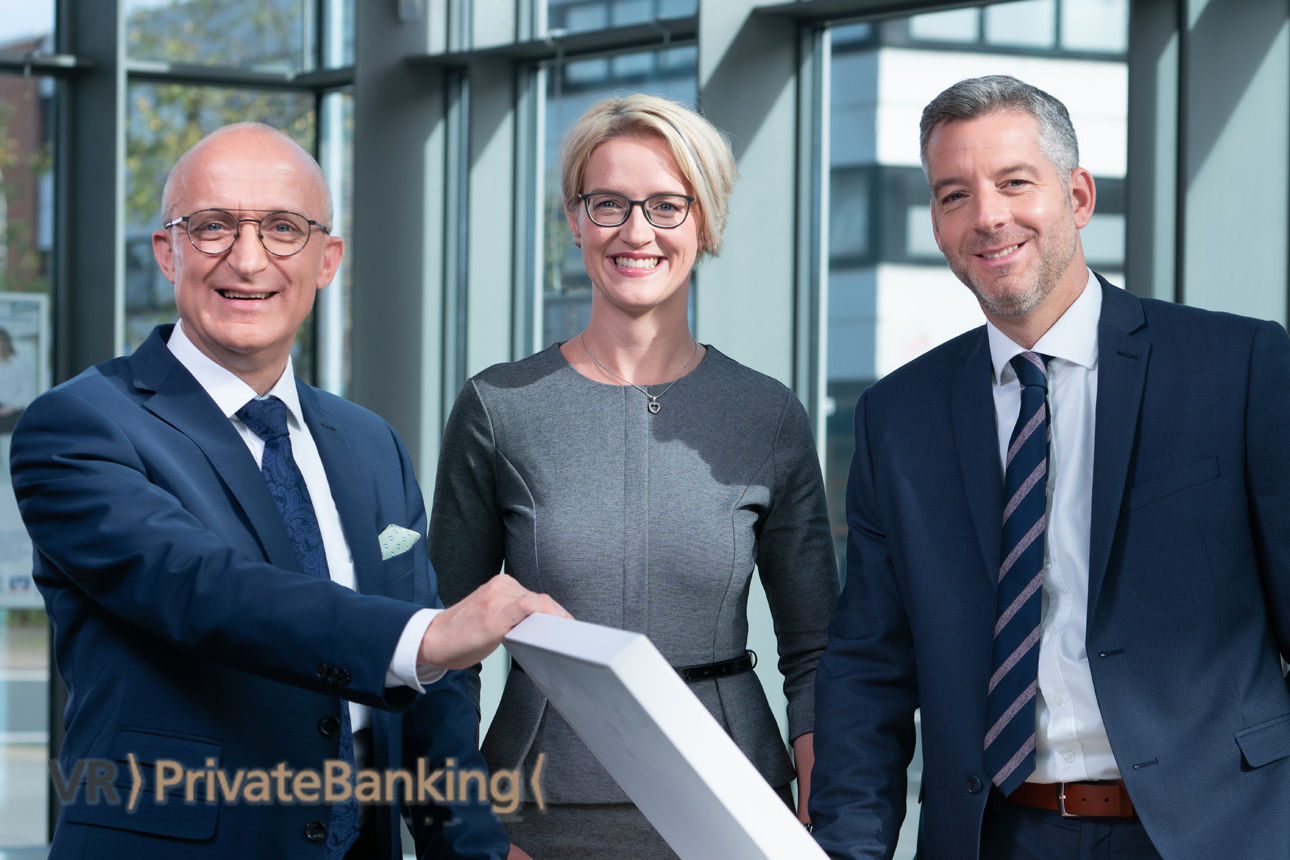 Drei Mitarbeiter des VR PrivateBanking schauen in die Kamera
