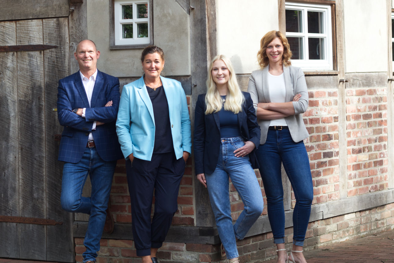Ein Mann und drei Frauen lehnen an einer Hauswand