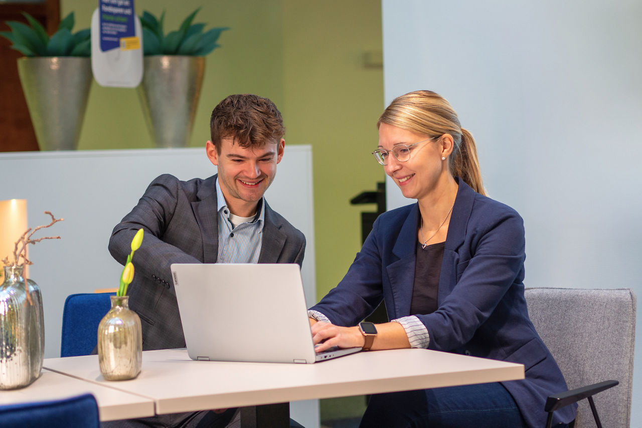 Ein Mann und eine Frau schauen auf einen Laptop