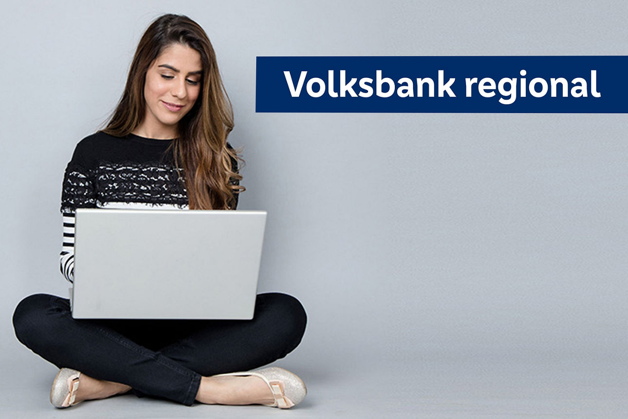 Eine Frau sitzt auf dem Boden, konzentriert auf ihren Laptop, mit einer entspannten Haltung und einem nachdenklichen Gesichts