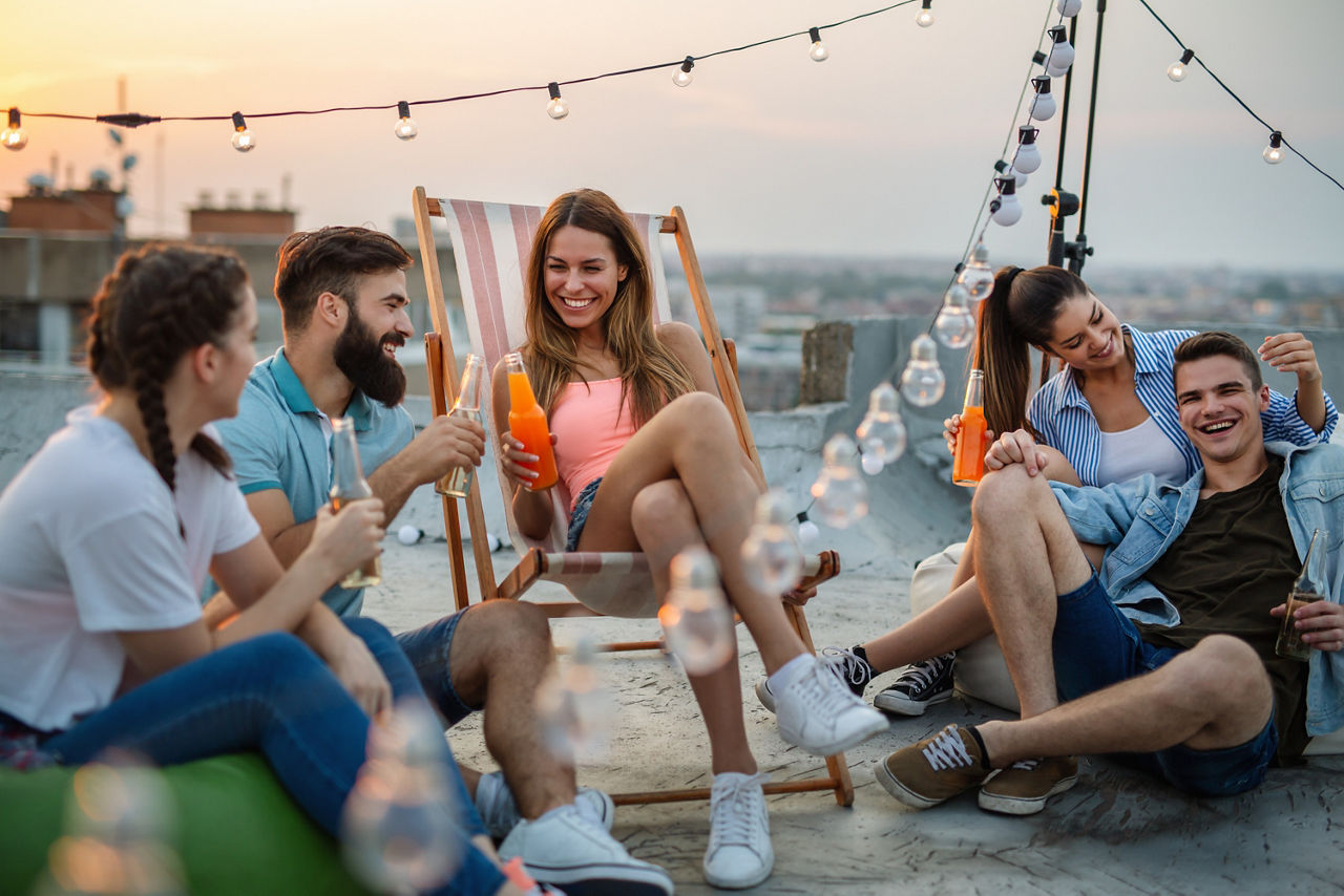 Eine Gruppe junger Menschen sitzt auf einer Dachterrasse. 