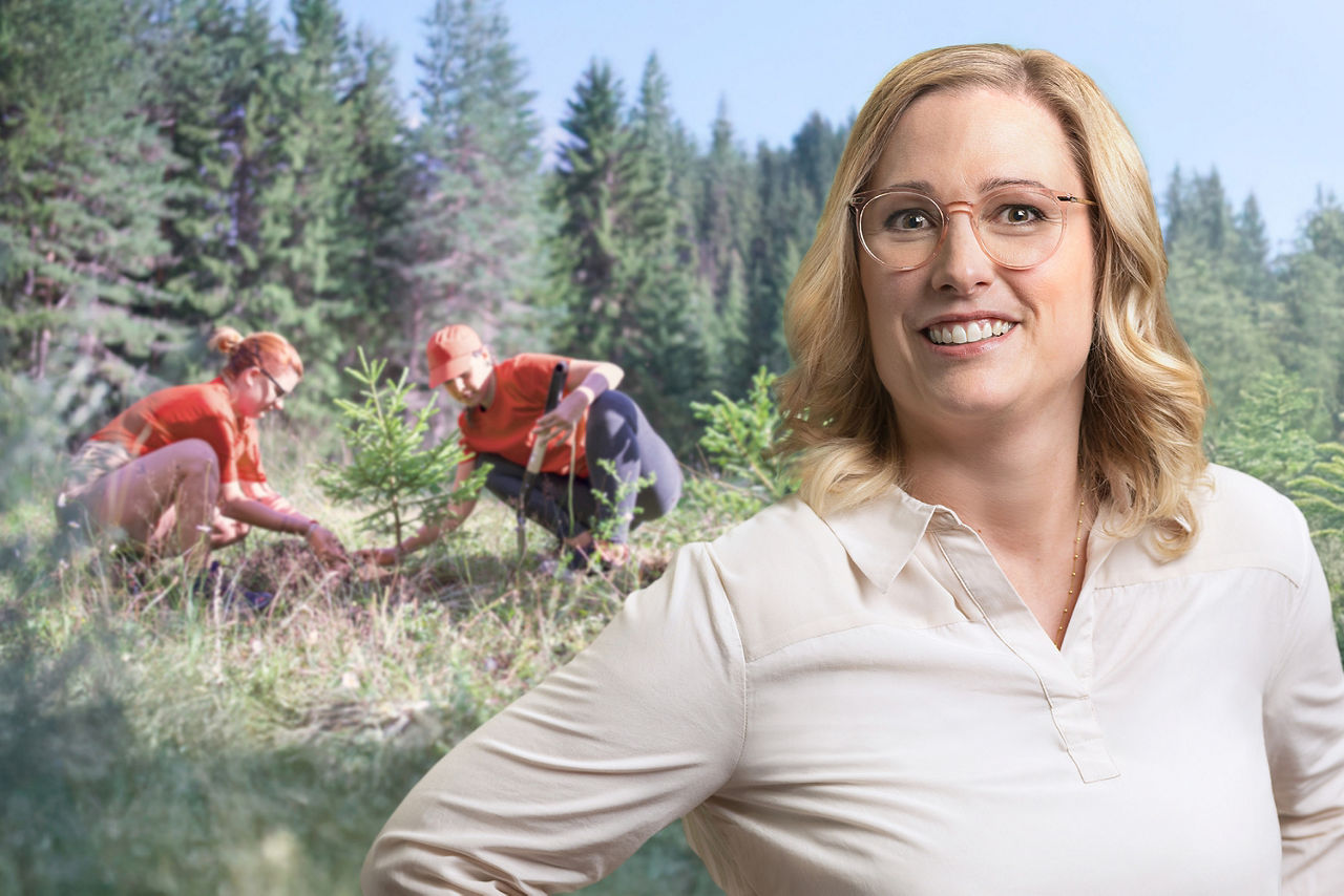Daniela Probandt im Wald vor einer Frau und einem Mann, die einen Baum pflanzen