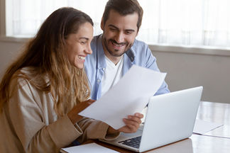 Eine Frau und ein Mann sitzen mit einem Dokument vor einem Laptop