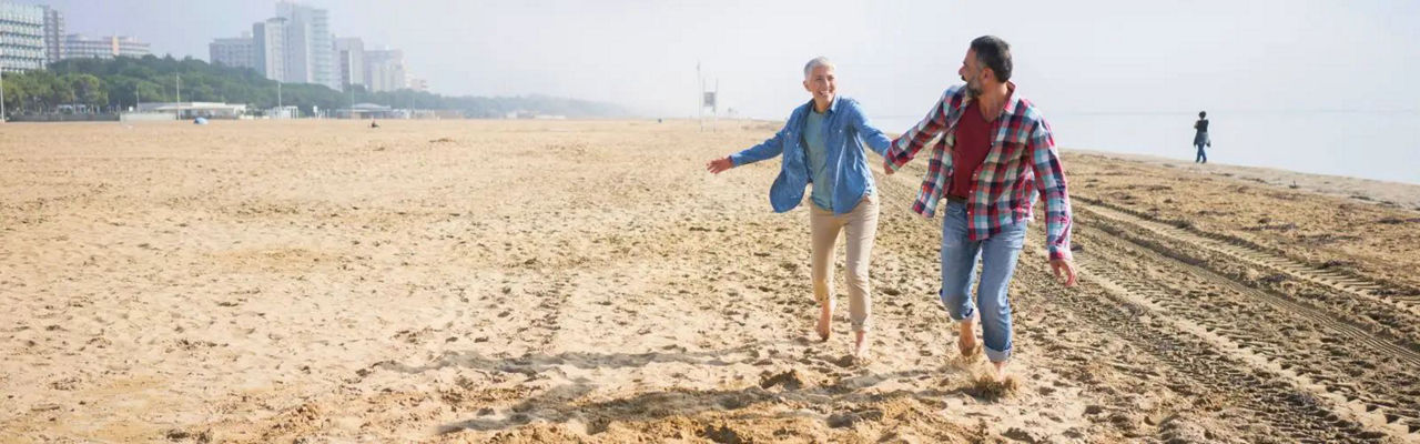 Ein Paar spaziert am Strand, Händchen haltend, mit den Wellen des Meeres