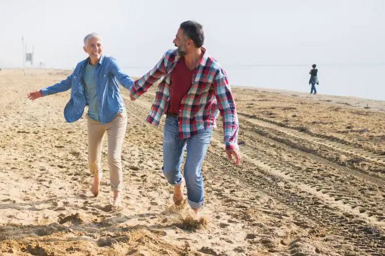 Ein Paar spaziert am Strand, Händchen haltend, mit den Wellen des Meeres