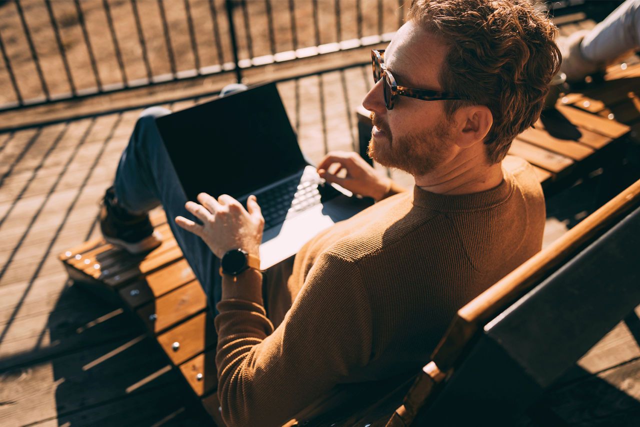 Mann arbeitet in der Sonne am Laptop