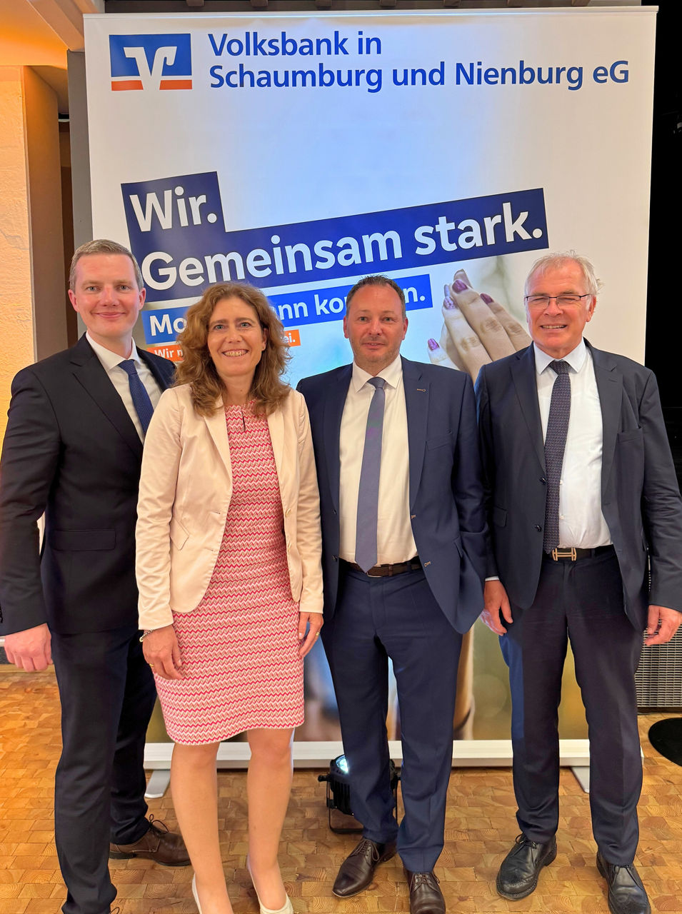 Drei Männer und eine Frau stehen von einer Leinwand