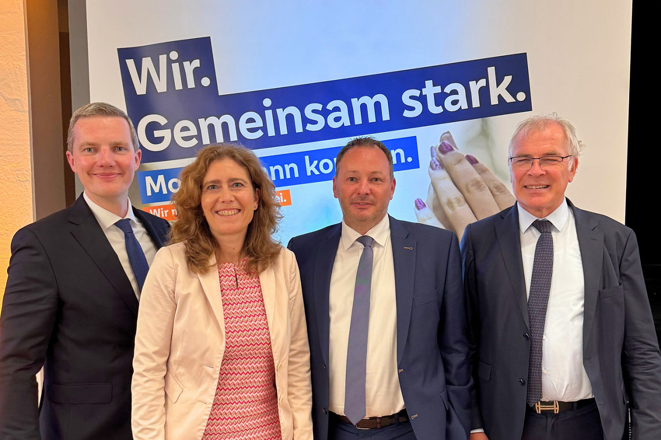 Drei Männer und eine Frau stehen von einer Leinwand