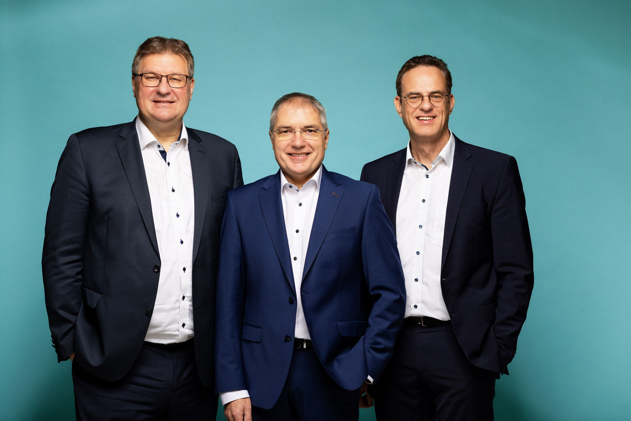 3 Vorstände vor einfarbigem Hintergrund