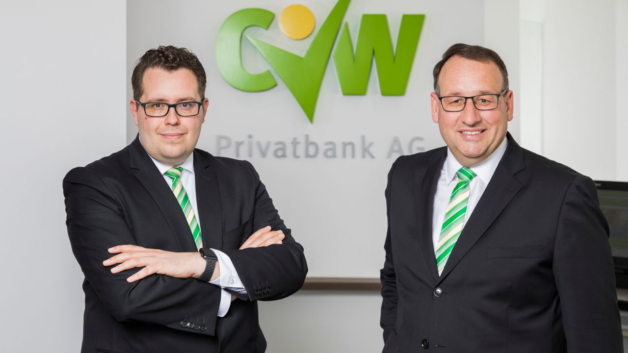 Unsere Vorstände stehen vor dem Logo der Bank